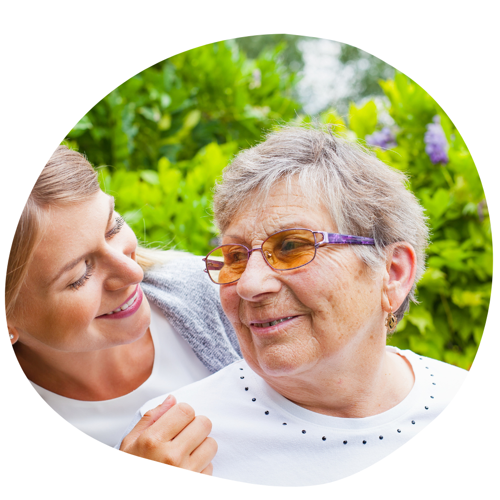 An elderly lady in her garden being comforted by a younger female.